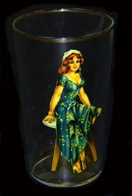 A mid century risque glass tumbler printed with a lady seated upon a table, internally naked, 12cm high.