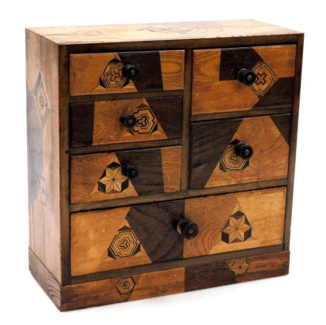 An early 20thC Japanese marquetry table chest, with an arrangement of three short, two deep and one long drawer, raised on a plinth base, 30cm high, 30cm wide.