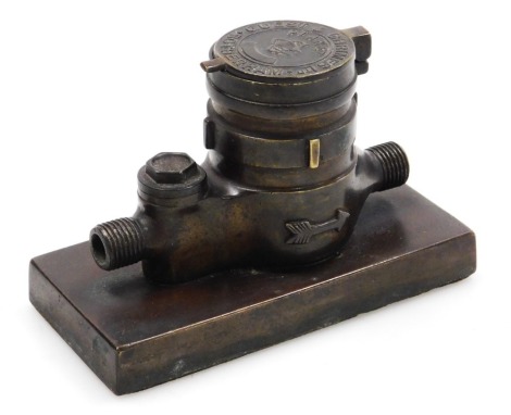 A late 19thC brass novelty inkwell, for Guest & Chrimes Ltd Rotheram, cast as a water meter fitting, on a rectangular base, 11.5cm wide.