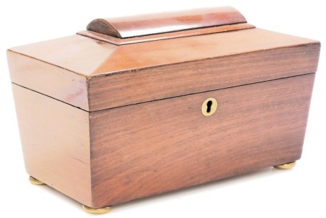 A Regency mahogany sarcophagus form tea caddy, the hinged lid opening to reveal twin lidded compartments, raised on brass bun feet, 25cm wide.