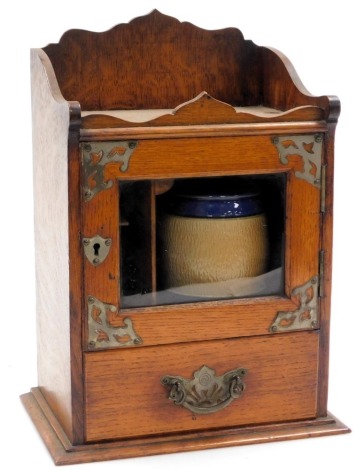 A Victorian oak smoker's cabinet, with a glazed door opening to reveal a fitted interior, with tobacco jar, above a frieze drawer, raised on a plinth base, 36cm high, 26.5cm wide, 17.5cm deep.