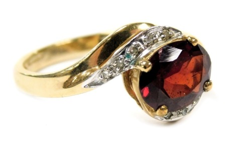 A 9ct gold and garnet single stone ring, in a crossover design, with diamond set shoulders, size O, 2.6g.