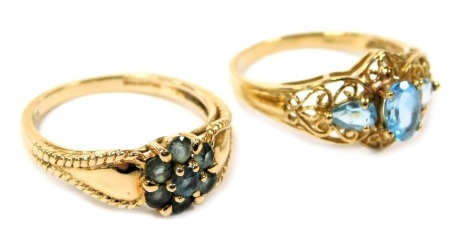 Two lady's 9ct gold and pale blue stone rings, one three stone in a stepped openwork setting, the other in a flower head setting, both size N, 4.3g.