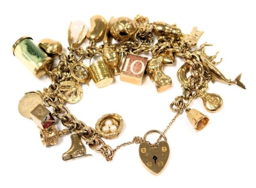 A 9ct gold charm bracelet, with twenty nine charms as fitted, on a heart shaped padlock clasp, with safety chain, 64.3g.