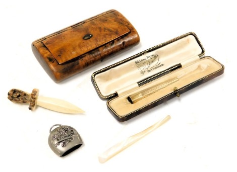 An early 20thC cigarette holder, with engraved decoration, mouthpiece lacking, yellow metal, stamped 9ct, 4.2g, a 19thC burr walnut snuff box, 10.5cm wide, a carved bone dagger brooch, Stainach souvenir cowbell, and a mother of pearl knife. (5)