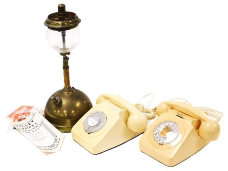 A brass and glass tilly lamp, with instructions, 35cm high, together with a cream dial telephone, and another in classic ivory, boxed. (3)