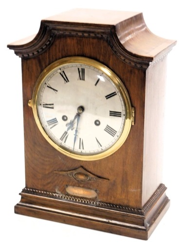 An Edwardian mahogany mantel clock, silvered dial bearing Roman numerals, Gustav Becker eight day movement, with rod strike, the case with a shaped pediment, raised on a plinth base, with presentation plaque, with pendulum and key, 35cm high, 25cm wide.