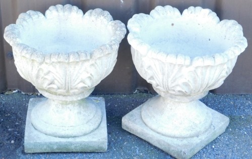 A pair of concrete planters, of circular leaf scroll form, raised on a square base, 32cm high, 31cm diameter.