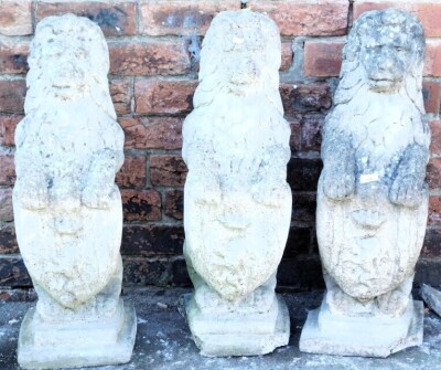 Three concrete garden figures, modelled as heraldic lions, each supporting a shield, raised on a stepped square base, 73cm high. (AF)