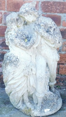 A concrete garden sculpture of a pair of lovers in embrace, raised on a circular base, 70cm high.