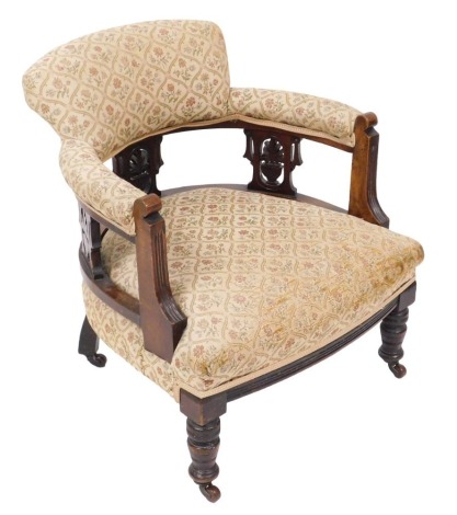 A late Victorian mahogany tub chair, upholstered in repeating floral pattern fabric, raised on turned legs, on castors, 59cm wide.