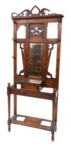 A Victorian oak hall stand, with a carved back with six hanging hooks, above a glove box, and galleried stand, raised on turned feet, united by an under tier, drip trays lacking, 179.5cm high, 76cm wide.