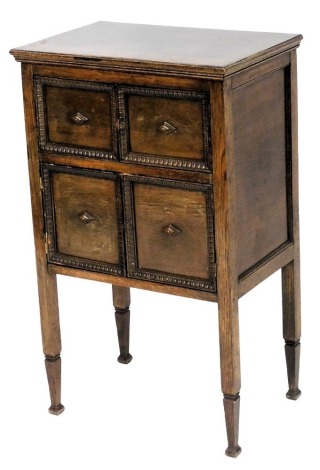 An early 20thC oak sewing cabinet, with a hinged lid above four panelled doors, raised on tapering square legs, 92cm high, 57cm wide, 37cm deep.