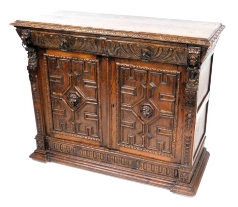 A Victorian oak cupboard, with a pair of foliate carved cushion drawers, above a pair of panelled doors centred with lion's head masks, flanked by lion's capped figural columns, raised on a plinth base, 98cm high, 122cm wide, 51cm deep.