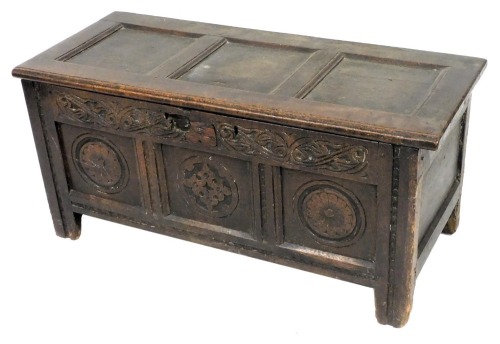 A 17thC oak coffer, with a triple panelled lid, above a carved frieze and floral panelled front, raised on stiles, 49cm high, 106cm wide, 45cm deep.