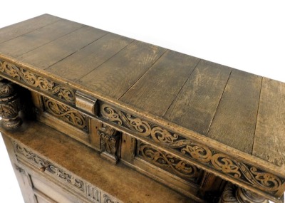 An Elizabethan style oak court cupboard, with a scrolling floral carved frieze, above a pair of panelled doors, flanking a caryatid, on carved cup and cover supports, above two frieze drawers over a pair of panelled doors, raised on stiles, 145cm high, 12 - 2