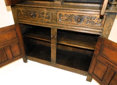 An Elizabethan style oak court cupboard, with a scrolling floral carved frieze, above a pair of panelled doors, flanking a caryatid, on carved cup and cover supports, above two frieze drawers over a pair of panelled doors, raised on stiles, 145cm high, 12 - 4