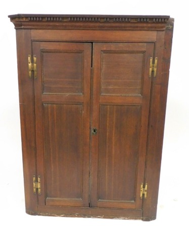 An 18thC oak wall hanging corner cupboard, with a dentil moulded pediment over two panelled doors opening to reveal three green painted shaped shelves, 108cm high, 82cm wide, 38cm deep.