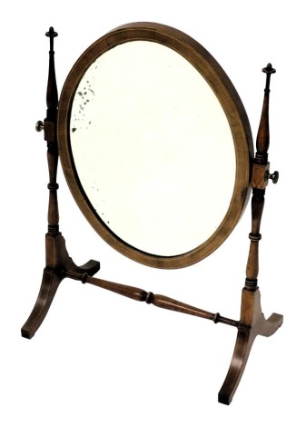 An Edwardian mahogany swing frame toilet mirror, with boxwood line inlay, and a bevelled oval glass mirror plate, 59cm x 41.5cm.