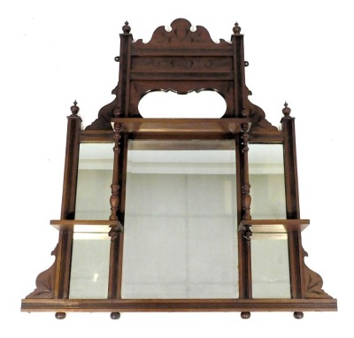 A Victorian mahogany framed overmantel mirror, with a carved pediment above floral carving and a shaped mirror, rectangular glass plate, flanked by two further glass plates with shelves to the front, 101cm x 74cm.