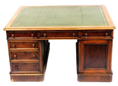 A Victorian mahogany partner's desk, with a gilt tooled green leather top, above one long and two short drawers, raised on a pedestal with three further drawers, the other with a cupboard door, the same to the other side, raised on plinth bases, 77cm high