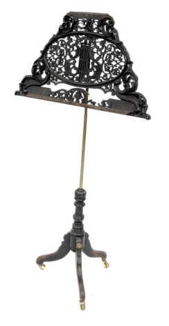 A Victorian ebonised music stand, with foliate carving, raised on a brass column and turned wooden base, over three cabriole legs, on brass castors, 123cm high.