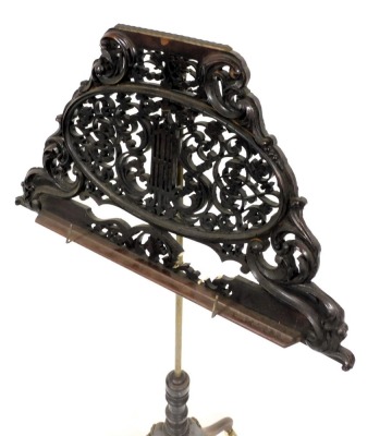 A Victorian ebonised music stand, with foliate carving, raised on a brass column and turned wooden base, over three cabriole legs, on brass castors, 123cm high. - 3