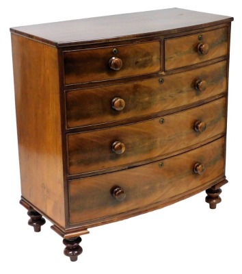 A George III mahogany bow front chest, of two short over three long drawers, raised on turned feet, 108cm high, 105cm wide, 53cm deep.