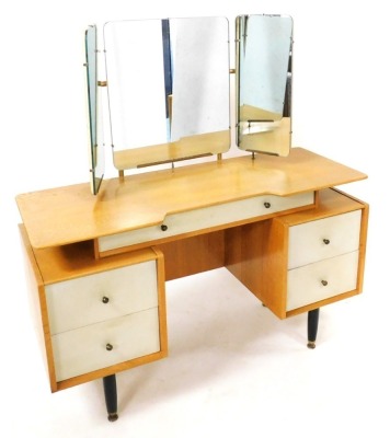 A mid century G-Plan bedroom suite, designed by E Gomme, comprising, a dressing table with a triptych mirror above one long drawer, over two pedestals each with two drawers, raised on brass capped turned legs, 135cm high, 124cm wide, 47cm deep, a double h - 3