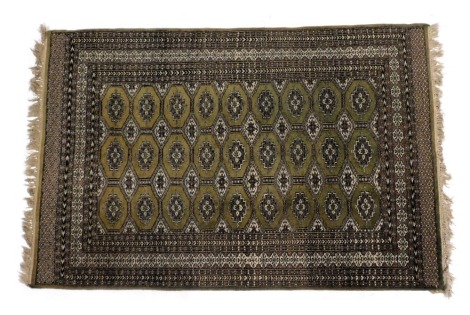 A Bokhara green ground rug, the central field with twenty seven large and sixteen smaller medallions, within repeating floral and geometric borders, 192cm x 121cm.