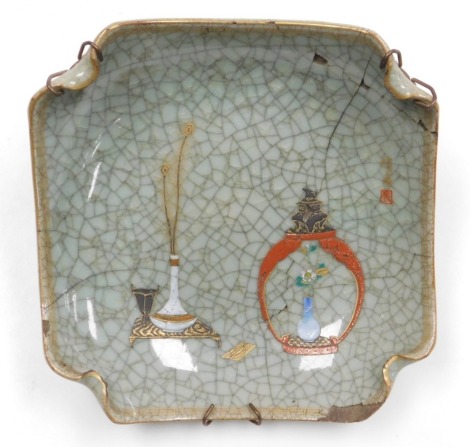 An early 20thC Chinese ge-type dish, of curved, square form, over painted with a vase of peacock feathers on a table, and an open jar and cover containing a vase of flowers, three character signature, six character mark to underside, 19cm wide (AF)