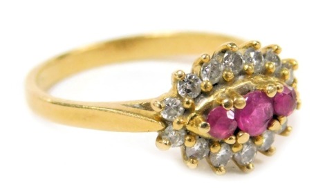 An 18ct gold ruby and diamond ring, with three central rubies in a surround of diamonds, size K, 3.1g.