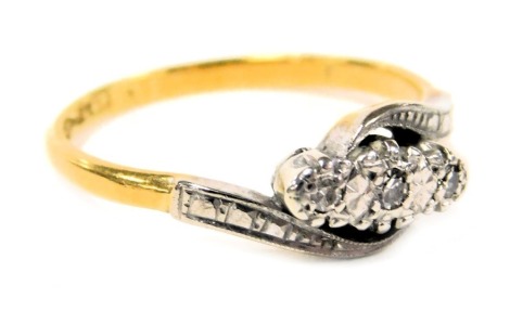 An 18ct gold diamond and platinum three stone ring, in a crossover setting, size M, 2.6g.