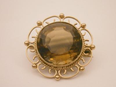 A yellow metal brooch set with a citrine.