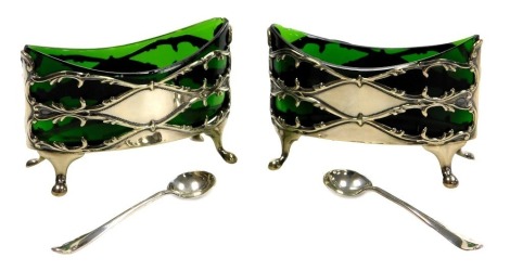 A pair of Edwardian silver salts, with green glass liners, raised on four paw feet, Birmingham 1906, together with a pair of salt spoons, Sheffield 1906, 3.02oz.