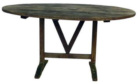 A Vendange pine grape harvest table, with an oval top tilt top, raised on a trestle base, 67.5cm high, 133cm wide, 110cm deep.