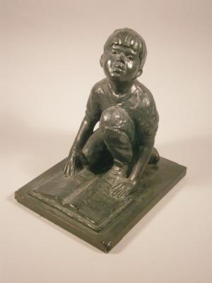 A bronzed plaster figure of a young boy reading a book by Gary Price