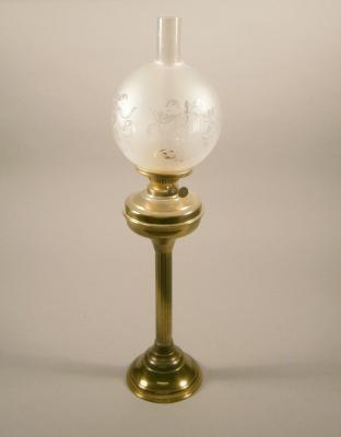 A brass oil lamp with a frosted shade and reeded column