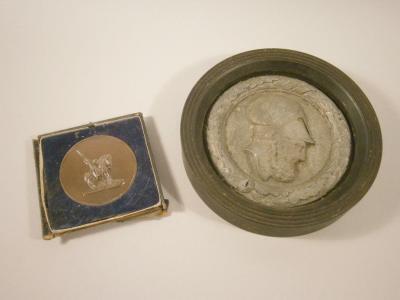 A cast metal plaque in the form of a Greek soldier wearing a helmet