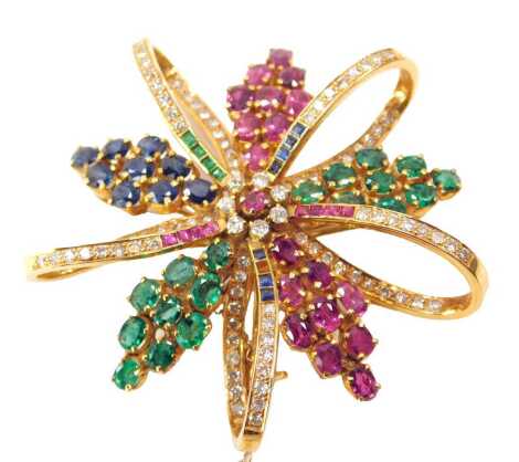 A diamond, emerald, sapphire and ruby brooch, of flowerhead and five petal form, interspersed with open work curls, in yellow metal, stamped 18c, with safety chain as fitted, one sapphire detached, 18.4g, 5cm wide.