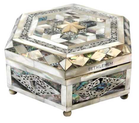 A hexagonal mother of pearl scent box, with various mother of pearl panelling central star inscribed Bethlehem, on bun feet, in a blue velvet lined interior, 8cm high, 18cm wide.