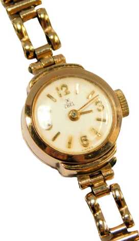 A 9ct gold Ebel lady's wristwatch, the small cream circular watch head set with numbers, 1cm wide, on box link bracelet, 11.4g all in.