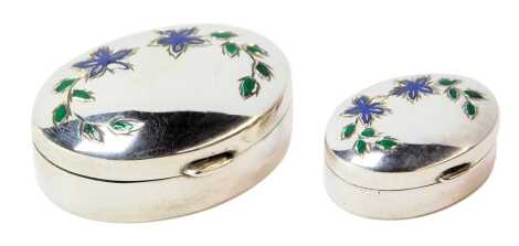 An Elizabeth II silver pill box, of oval form, with floral enamel decoration to top, London 1993, 4cm wide, together with a matching smaller example, 2.5cm wide, 0.59oz.