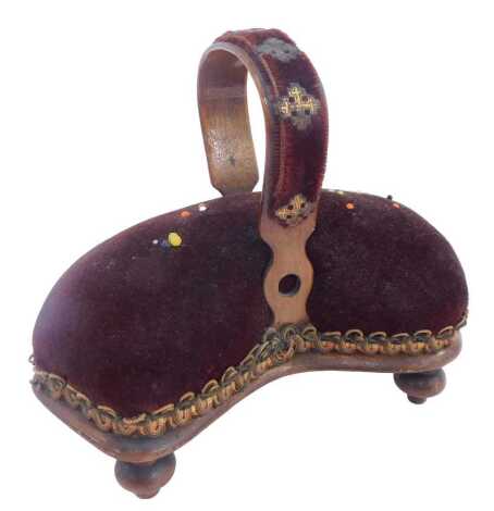 A Victorian pin cushion, of waisted form, with ring handle, raised on turned feet, 16cm high.