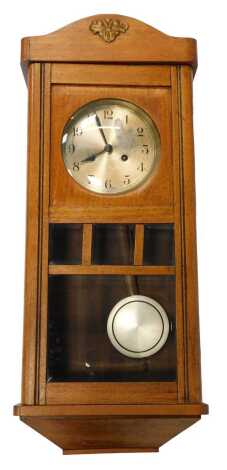 An early 20thC mahogany cased wall clock, the circular silvered dial bearing Arabic numerals, eight day, with pendulum, the case 71cm high.