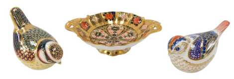 A group of Royal Crown Derby porcelain, comprising an imari patterned gold ground twin handled dish, printed marks, 13cm wide, and two bird paperweights, each with silver stoppers.