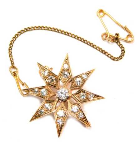 A diamond set star brooch, set with round brilliant cut diamonds, each claw set, the central stone 0.01ct, each petal bearing two stones, one 0.05ct, one 0.01ct, on a single pin back with safety chain and clasp, yellow metal unmarked, 2cm wide.