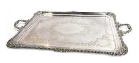 A Victorian silver plated twin handled tray, with a gadrooned border and shell and leaf decorated corners, the tray bright cut decorated with flowers, scrolls, etc, 62cm wide overall.