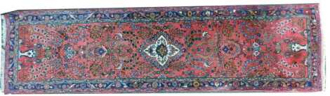 A Persian pink ground Hamadan runner, decorated centrally with floral medallion with floral sprays within one wide and two narrow borders, 282cm x 81cm.