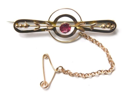 A garnet bar brooch, the oval central section set with single garnet with pierced shoulders, on single pin back with safety chain, yellow metal, stamped 9ct, 3.3g all in.